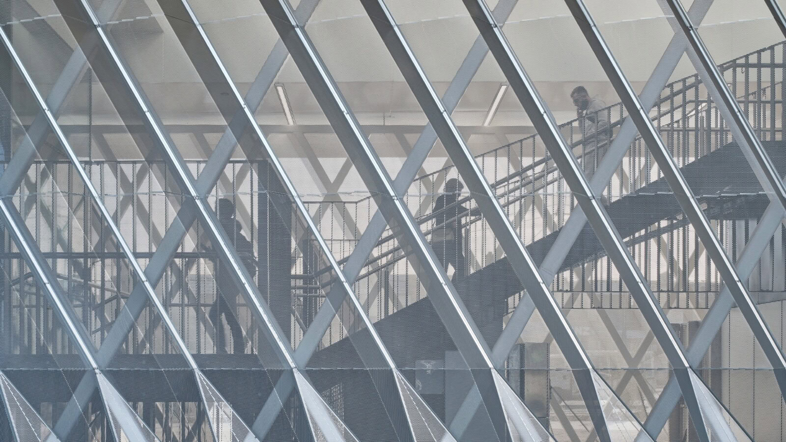 Commuters moving through stairs behind translucent canopy at Reservoir Station – Genton’s elevated rail architecture in Melbourne