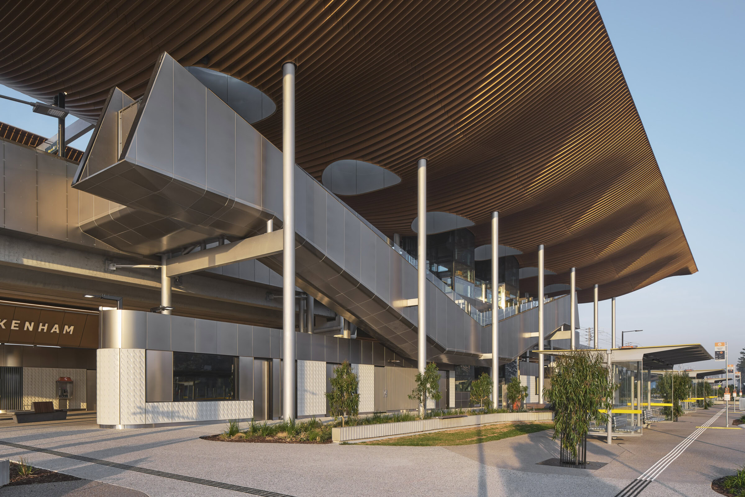 Pakenham Station Melbourne rail architecture with sculptural bronze soffit, elevated stairs and formal civic colonnade