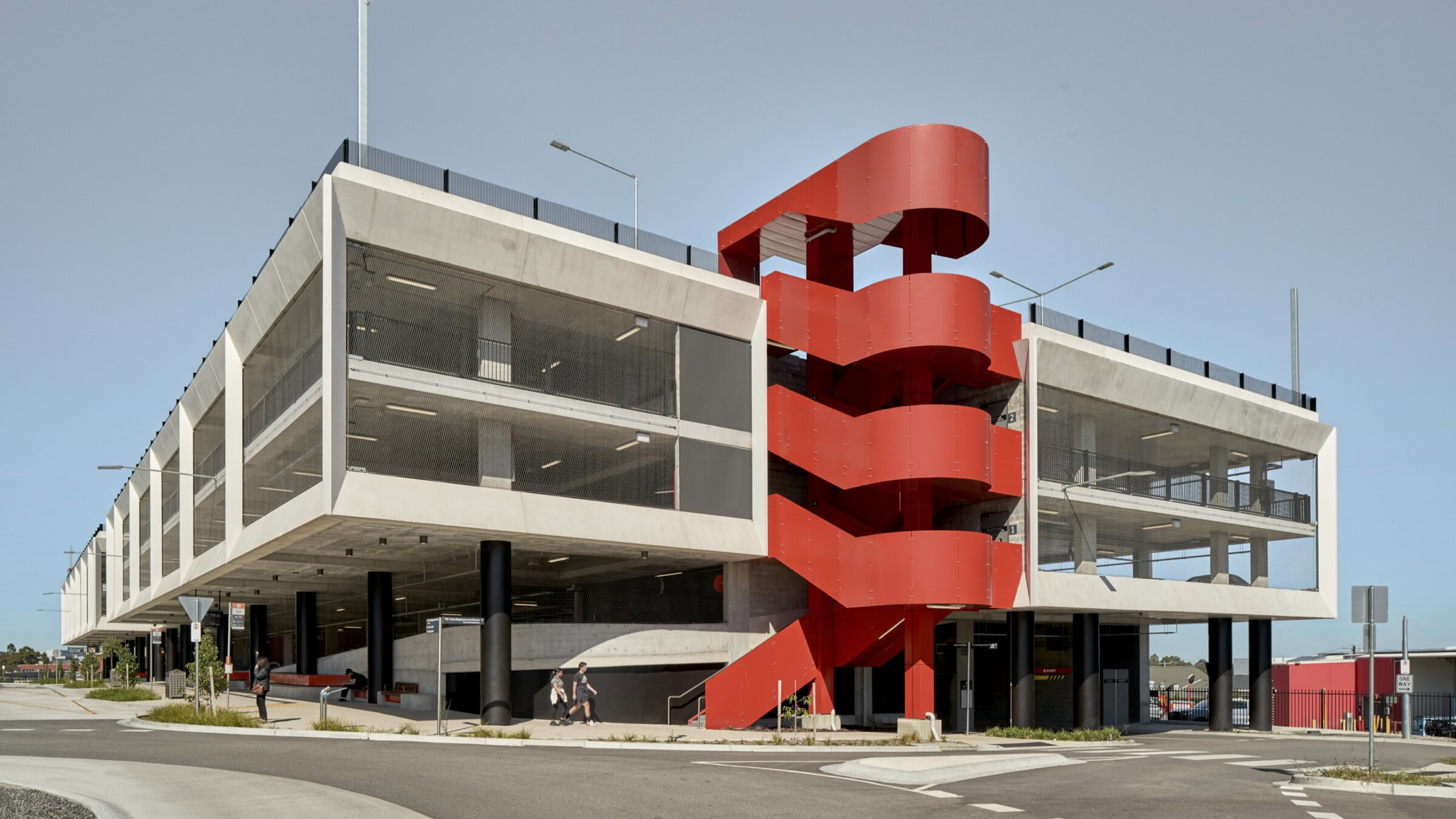 Multi level car park with striking red staircase designed by Genton as part of an integrated transport interchange, showcasing aviation and transport interchange expertise.